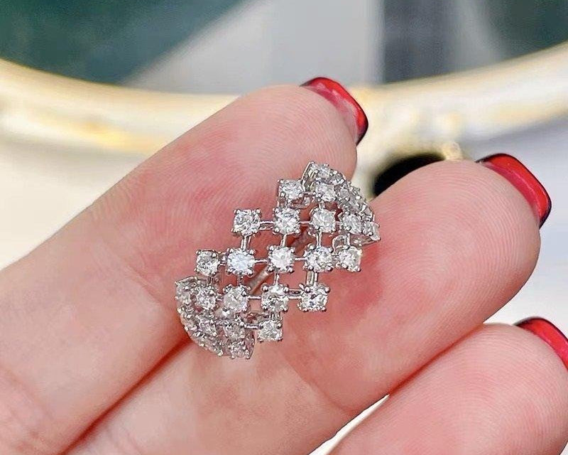 Diamond earring held between fingers with a blurred background