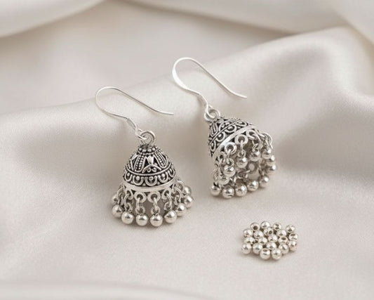 Silver earrings with pearl-like beads on a white fabric background