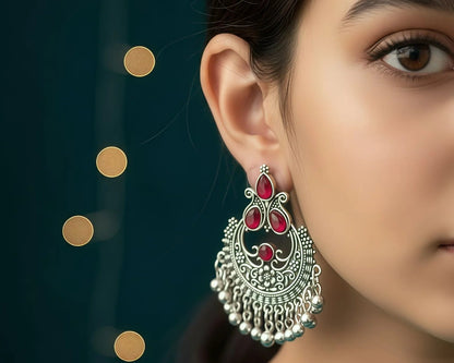 Close-up of a woman wearing a silver and red earring with a dark background