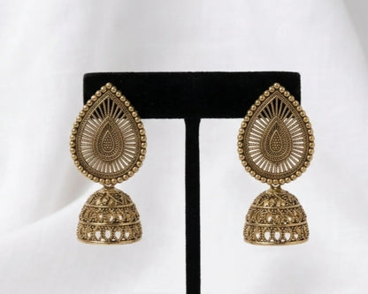 Gold teardrop earrings on a black earring stand against a white background