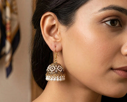 Close-up of a woman wearing gold earrings with pearl accents.