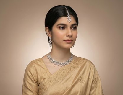 Woman wearing a beige saree with jewelry against a beige background