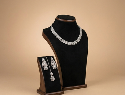 Jewelry set with necklace and earrings on a black velvet stand against a beige background