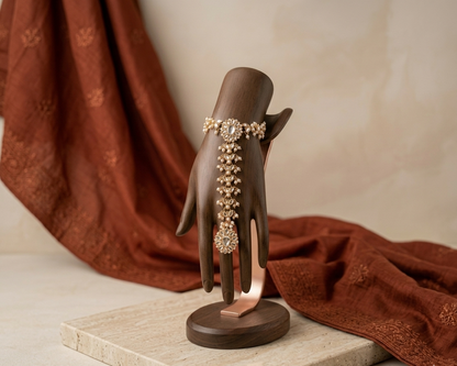 Decorative hand with jewelry on a wooden stand against a brown fabric background