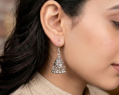 Silver earrings worn by a person with a neutral background