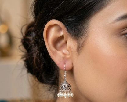 Close-up of a woman wearing a silver earring with pearls.