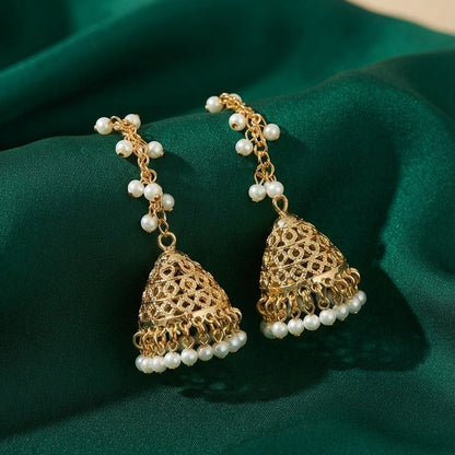 A pair of gold-toned jhumka earrings with white pearl bead accents, displayed on a draped dark green satin fabric.