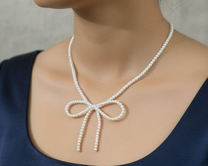 Pearl necklace with a bow design worn by a person against a neutral background