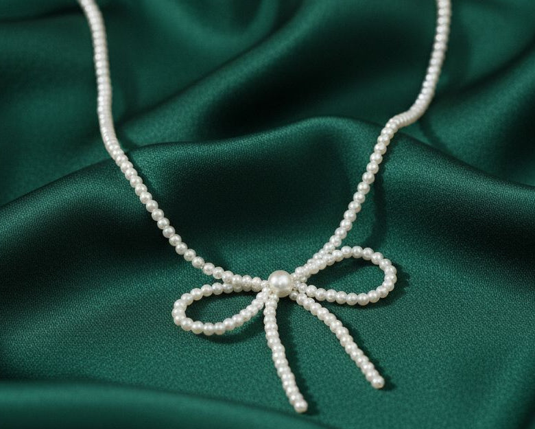 Pearl necklace with a bow on a green satin background