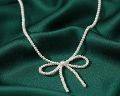 Pearl necklace with a bow on a green satin background