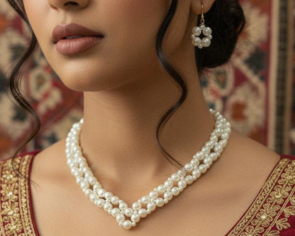 Woman wearing a pearl necklace and earrings with a red and gold embroidered outfit.