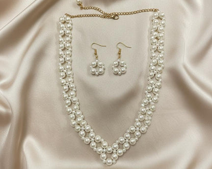 Pearl necklace and earrings set on a beige fabric background