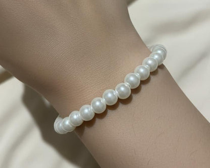 Pearl bracelet on a person's wrist with a neutral background