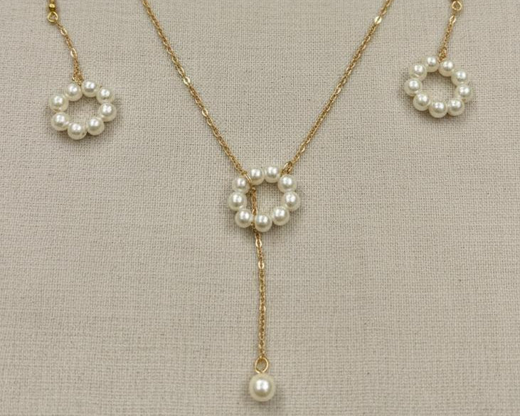 Pearl necklace and earrings set on a neutral background