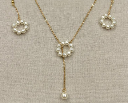 Pearl necklace and earrings set on a neutral background