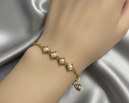 Gold bracelet with pearls on a hand against a gray fabric background