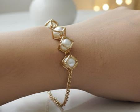 Gold bracelet with square gemstones on a wrist against a blurred background