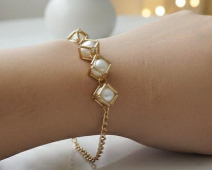 Gold bracelet with square gemstones on a wrist against a blurred background