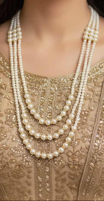 Woman wearing a pearl necklace and earrings on an embroidered outfit