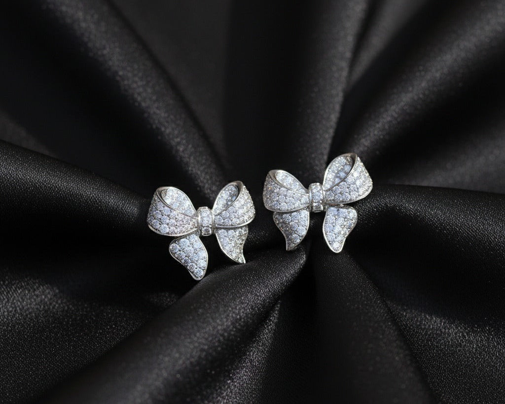 Bow-shaped earrings on black satin fabric