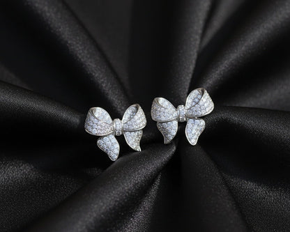 Bow-shaped earrings on black satin fabric