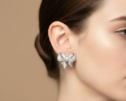 Close-up of a woman wearing a bow-shaped earring with a neutral background