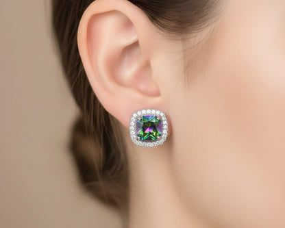 Close-up of an ear wearing a colorful gemstone earring with a blurred background