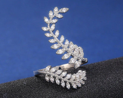 Silver leaf-shaped earring on a black stand with a blue background