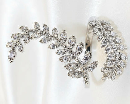 Silver leaf-shaped ring with clear gemstones on a white background