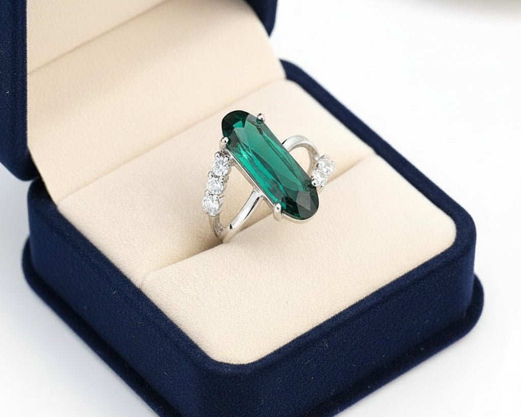 Green gemstone ring in a blue jewelry box on a white background