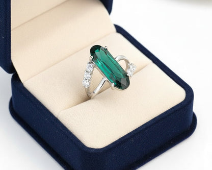 Green gemstone ring in a blue jewelry box on a white background