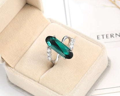 Green gemstone ring with silver setting on a beige jewelry box