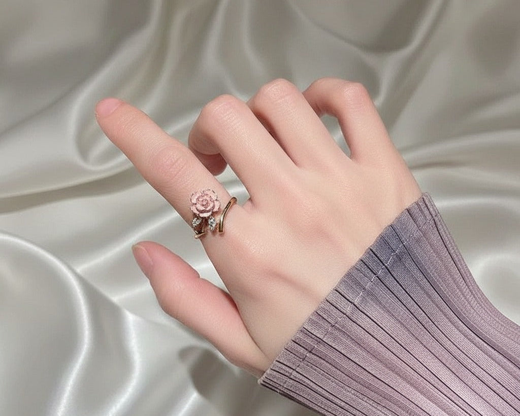 Hand wearing a ring with a rose design on a satin background