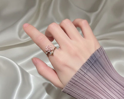 Hand wearing a ring with a rose design on a satin background