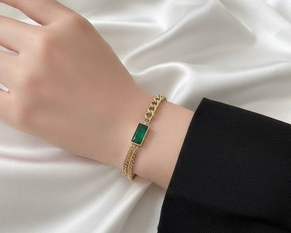 Gold bracelet with a green gemstone on a white fabric background