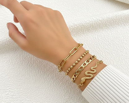 Hand wearing multiple gold bracelets on a white background