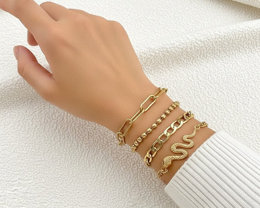 Hand wearing multiple gold bracelets on a white background