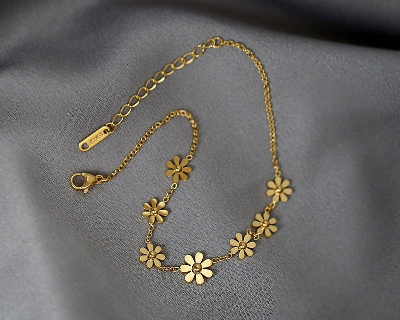 Gold floral necklace on a gray fabric background