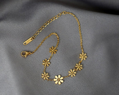 Gold floral necklace on a gray fabric background