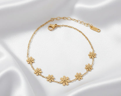 Gold bracelet with floral designs on a white satin background