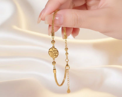 Gold bracelet held by a hand against a soft beige background