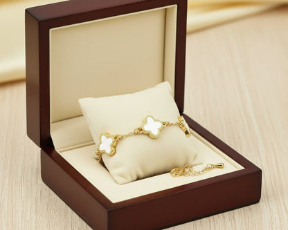 Gold bracelet with butterfly design in a wooden jewelry box on a beige fabric background