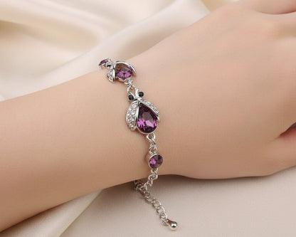 Silver bracelet with purple gemstones on a hand against a beige fabric background