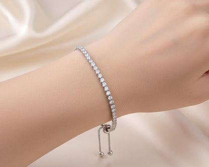 Silver bracelet with small stones on a wrist against a soft beige background
