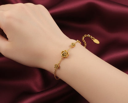Gold bracelet with a rose design on a wrist against a burgundy satin background