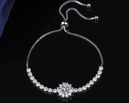 Silver bracelet with a floral clasp on a dark background