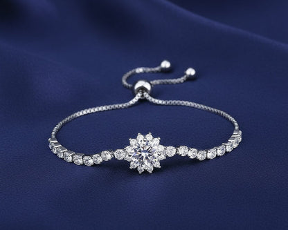 Silver bracelet with a diamond-like clasp on a blue fabric background