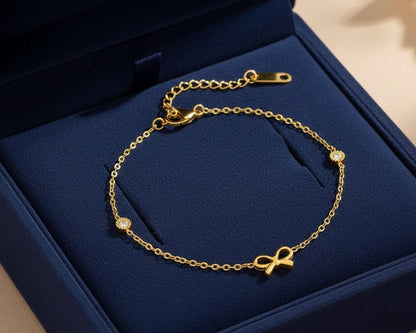 Gold bracelet with bow detail on a blue jewelry box