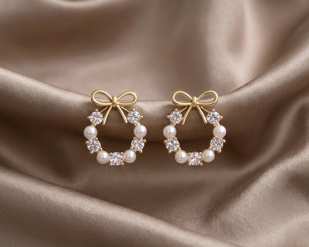 Pair of gold hoop earrings with pearl and diamond accents on a satin surface