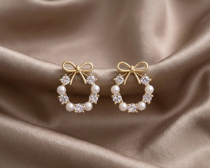 Pair of gold hoop earrings with pearl and diamond accents on a satin surface